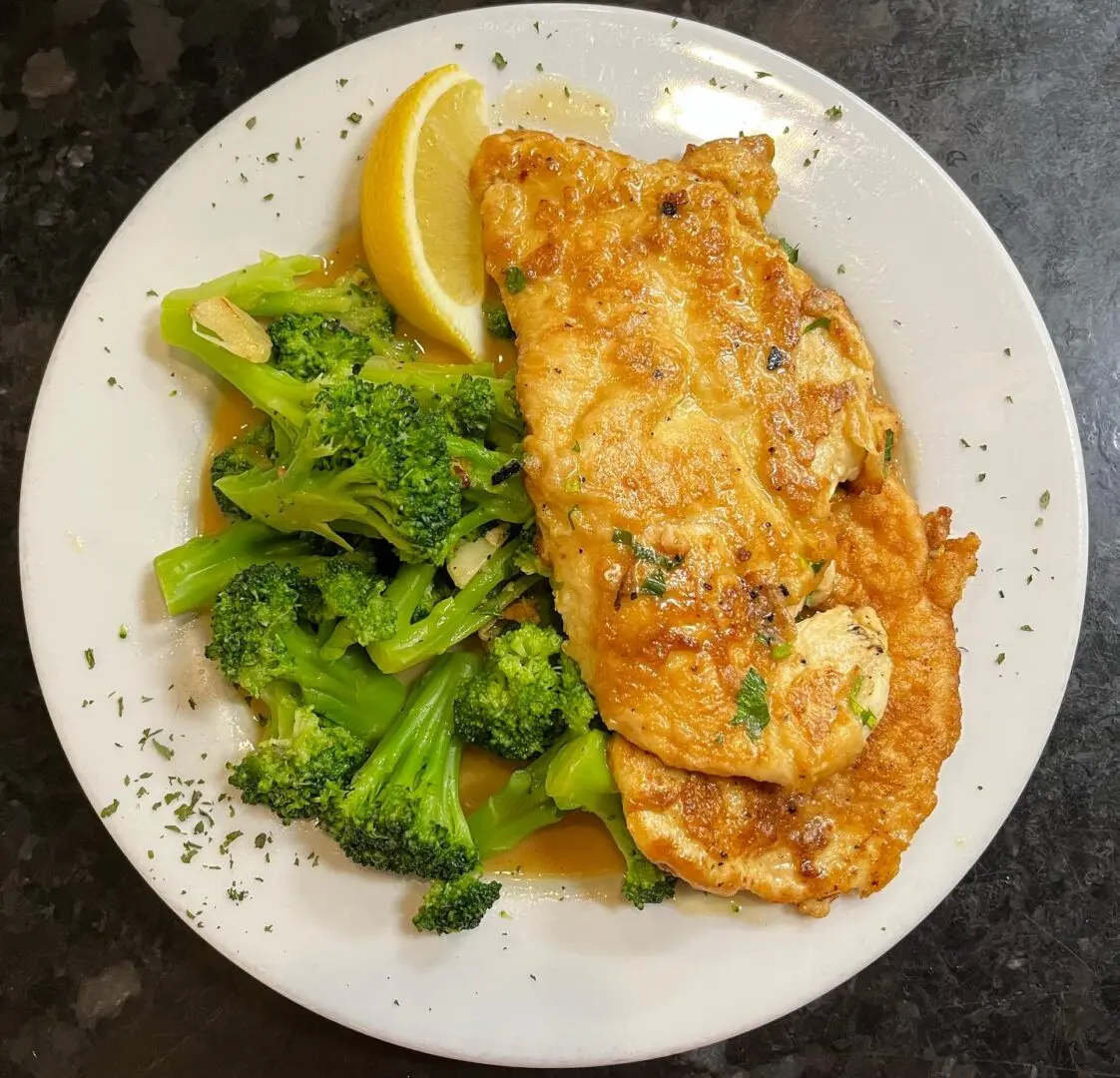 A plate of food with broccoli and lemon.