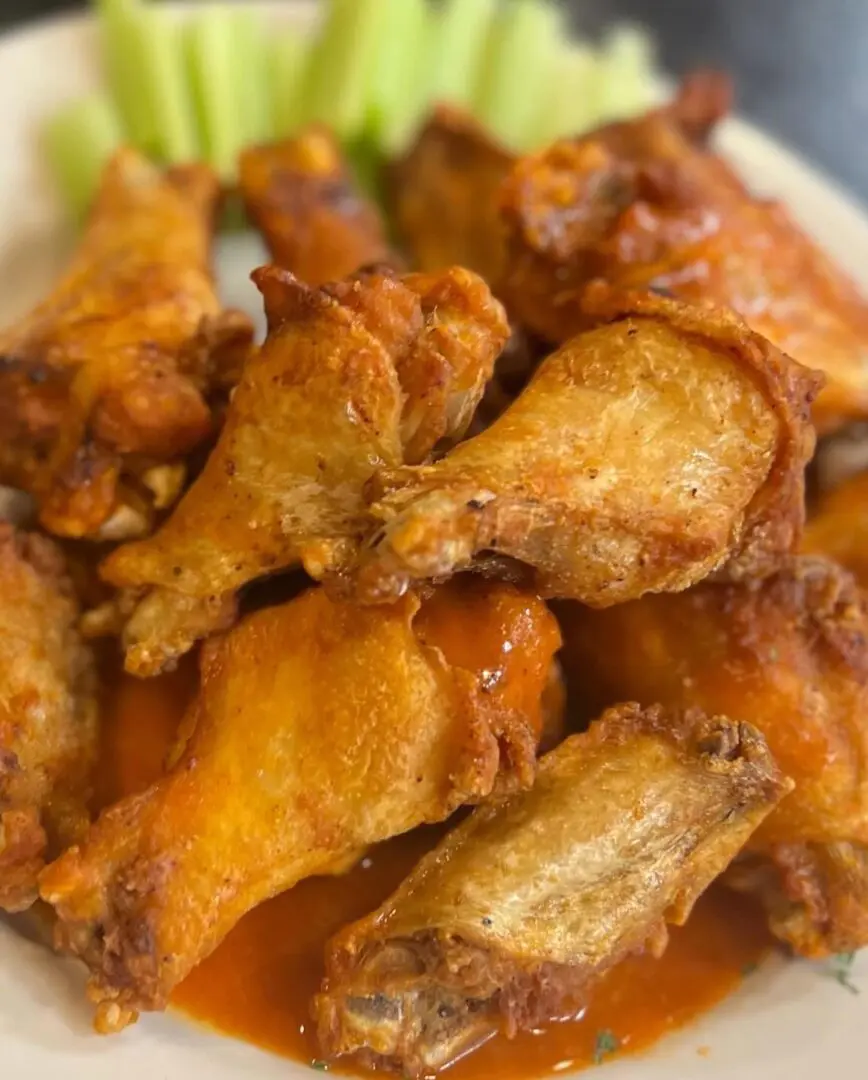 A plate of chicken wings with sauce on top.