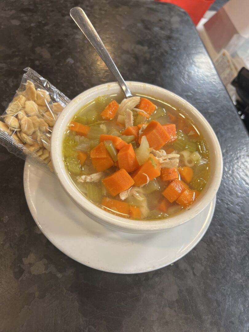 A bowl of soup with carrots and nuts on the side.