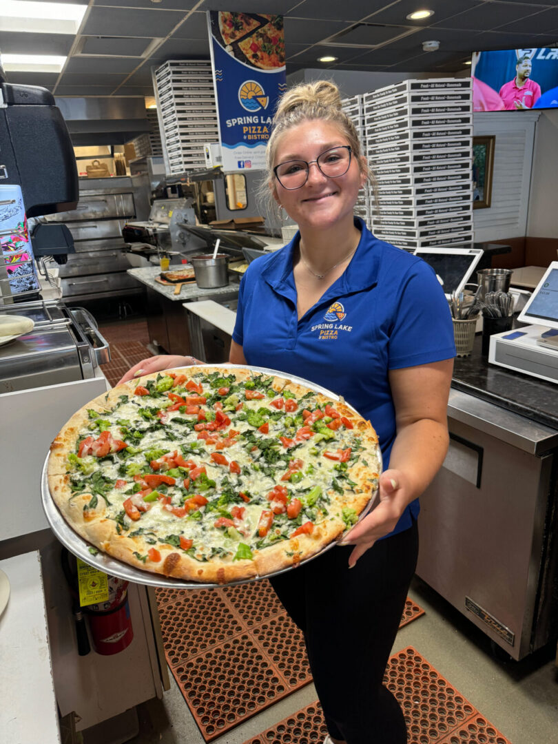 Spring Lake Pizza employee holding large pizza with beautiful vegetables